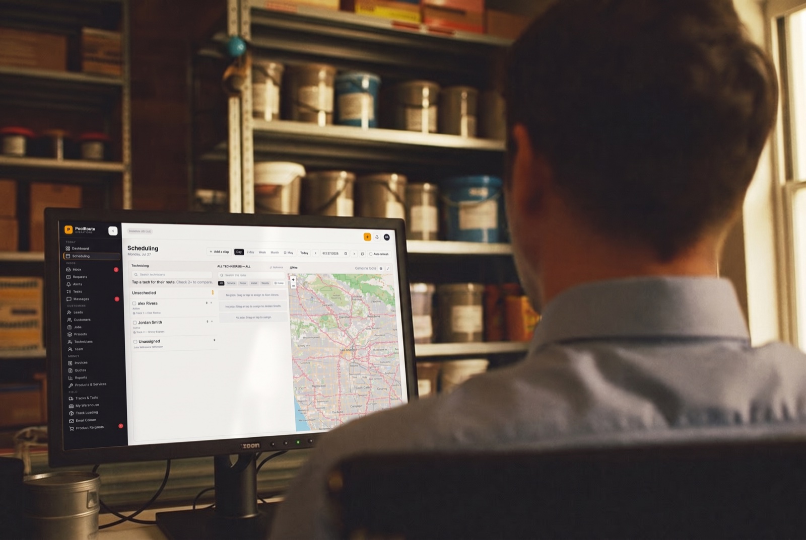 Pool-store manager at a warehouse desktop watching the live dispatch board and route map
